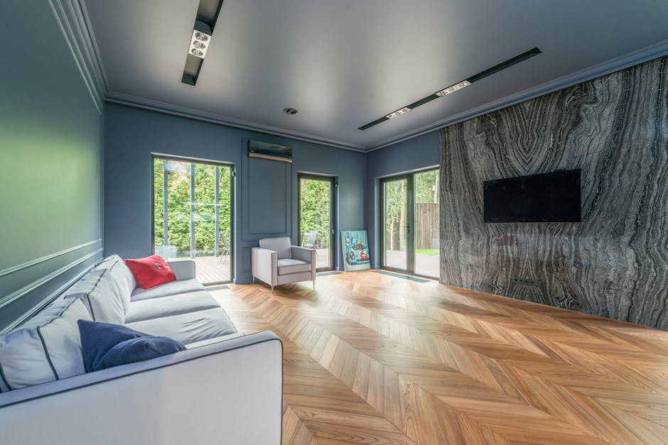 Spacious living room with marble wall, chevron wooden flooring, and ample natural light.