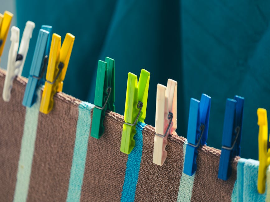 Bright clothes pegs holding striped towels on an outdoor clothesline, showcasing a colorful laundry scene.