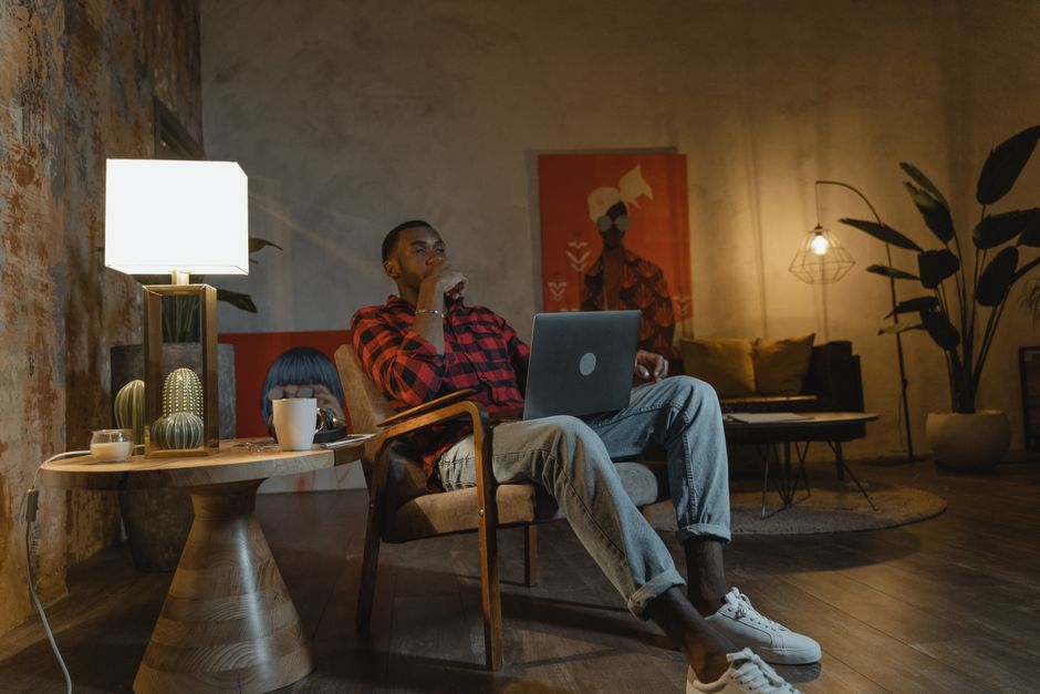 Man in a cozy living room setting relaxes with a laptop, enjoying a warm ambiance.