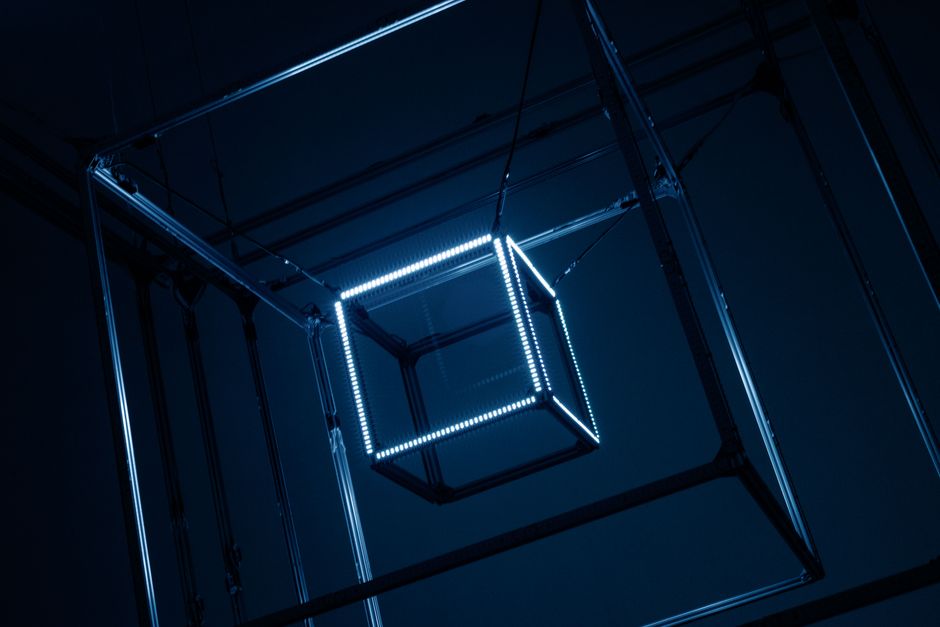 Close-up of illuminated geometric cubes hanging with metal frames in a dark setting.