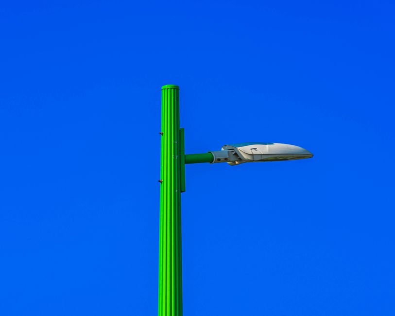 Vibrant green street light set against a deep blue sky, showcasing urban minimalism.