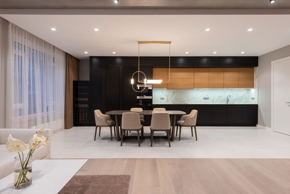 Modern house interior with table with chairs next to open plan kitchen and window with curtain near sofa