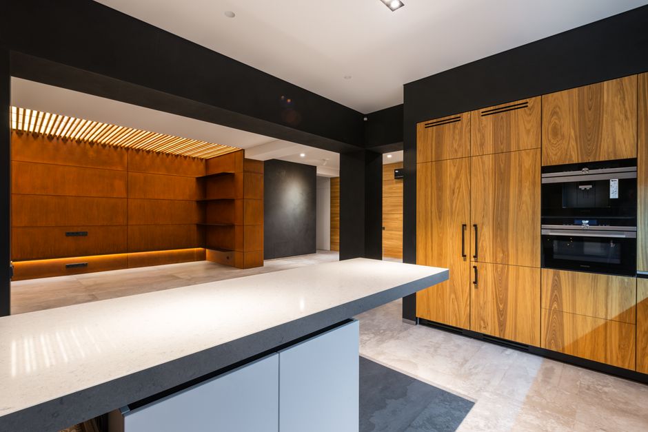 Modern kitchen and passage interior with built in oven against table on tiled floor at home