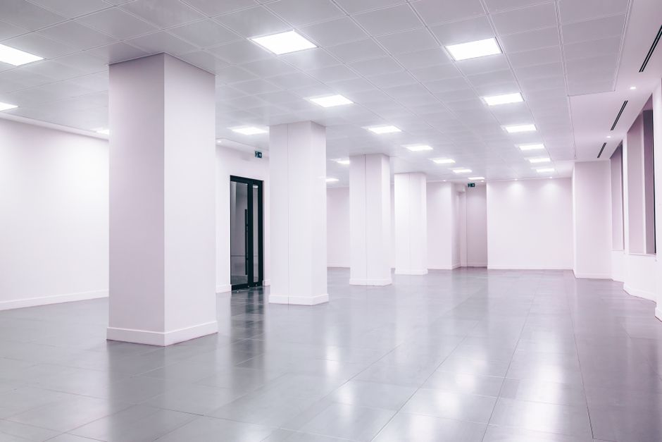 Wide-angle view of a modern minimalist white office space with clean lines and ample lighting.