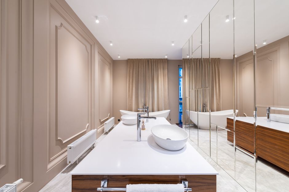 Interior of stylish bathroom with white ceramic sink and bath placed in contemporary apartment