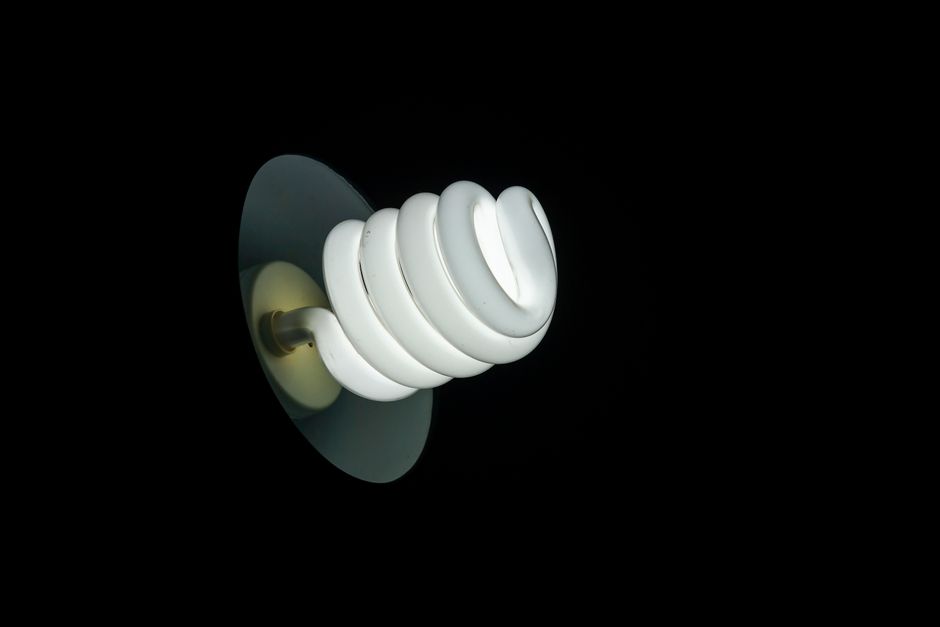 Close-up of a glowing spiral light bulb highlighting modern design in darkness.