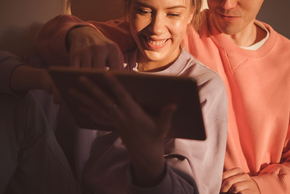 A joyful couple enjoying leisure time and bonding over a digital tablet at home.