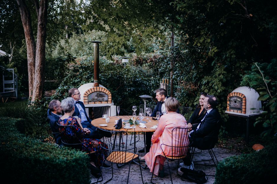 A sophisticated gathering of adults enjoying an evening dinner party in a lush garden setting.