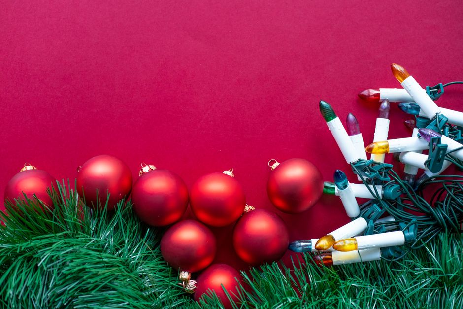 Colorful Christmas lights and red ornaments on a festive background.